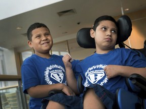 In this Aug. 29, 2017 photo provided by Boston Children's Hospital, Brian Rojas smiles while standing next to his brother Brandon at Boston Children's Hospital. The boys suffer from adrenoleukodystrophy, an inherited nerve disease featured in the movie "Lorenzo's Oil."  Brian was able to benefit from an experimental treatment while the disease had progressed too far in Brandon to qualify for the gene therapy study.  Study results were published Wednesday, Oct. 4 by the New England Journal of Medicine and discussed at the Child Neurology Society conference in Kansas City. (Katherine C. Cohen/Boston Children's Hospital via AP)