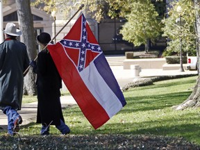 FILE - In this Jan. 19, 2016 file photo, a couple leaves the grounds of the state Capitol in Jackson, Miss., after participating in a rally in support of keeping the Confederate battle emblem on the state flag. Attorneys say in written arguments to U.S. Supreme Court that the Confederate battle emblem on the Mississippi flag is "an official endorsement of white supremacy" and lower courts were wrong to block a lawsuit challenging the flag. The arguments were made in papers filed Friday, Oct. 27, 2017,  by lawyers for Carlos Moore, an African-American attorney who sued the state in 2016 seeking to have the flag declared an unconstitutional relic of slavery.  (AP Photo/Rogelio V. Solis, File)