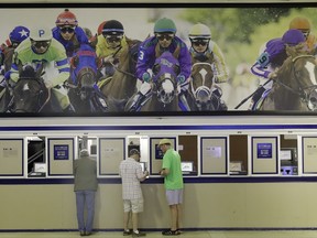 FILE - In this May 19, 2017 file photo, fans place bets ahead of the running of the Black-Eyed Susan horse race at Pimlico race course in Baltimore. Legal sports betting could be offered in 32 states within five years if the U.S. Supreme Court rules in favor of New Jersey's quest to offer such gambling, according to a new report. Major professional and collegiate sports leagues oppose New Jersey's effort to legalize sports betting, saying it would threaten the perceived integrity of the games. (AP Photo/Patrick Semansky, File)