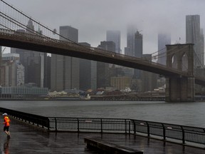 A runner moves along the Brooklyn shoreline of the East River as rain and clouds loom over lower Manhattan on the fifth anniversary of Superstorm Sandy Sunday, Oct. 29, 2017, in New York. (AP Photo/Craig Ruttle)