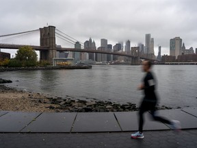 A runner passes along the Brooklyn shoreline of the East River as rain and clouds loom over lower Manhattan on the fifth anniversary of Superstorm Sandy Sunday, Oct. 29, 2017, in New York. (AP Photo/Craig Ruttle)