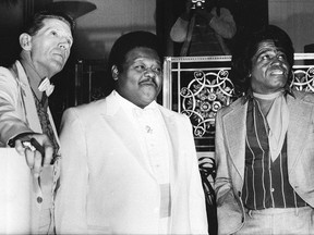 FILE - This Jan. 23, 1986 file photo,  from left, musicians Jerry Lee Lewis,  Fats Domino and James Brown pose at a reception where they were inducted into the Rock and Roll Hall of Fame at the Waldorf-Astoria Hotel in New York.  Domino, the amiable rock 'n' roll pioneer whose steady, pounding piano and easy baritone helped change popular music even as it honored the grand, good-humored tradition of the Crescent City, has died. He was 89. Mark Bone, chief investigator with the Jefferson Parish, Louisiana, coroner's office, said Domino died Tuesday, Oct. 24, 2017. (AP Photo/G. Paul Burnett)