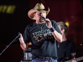 FILE - In this June 7, 2017 file photo Jason Aldean performs during a surprise pop up concert at the Music City Center in Nashville, Tenn. Aldean is set to make an emotional return to the stage, Thursday, Oct. 12 in Tulsa, Oklahoma, after cancelling tour dates following the mass shooting in Las Vegas. The singer was onstage Oct. 1 when a gunman sprayed bullets into the crowd at the outdoor Route 91 Harvest festival, killing dozens of people and leaving hundreds injured.  (Photo by Amy Harris/Invision/AP, File)