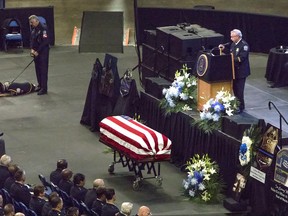 In this photo provided by WBFO News, the casket of Buffalo Police Officer Craig Lehner is positioned in front of the state at Key Bank Center, during Lehner's funeral in Buffalo, N.Y., Wednesday, Oct. 25, 2017. Lehner was killed in a training dive accident in the Niagara River on Oct. 13. At top left is his canine partner Shield. (Eileen Koteras Elibol/WBFO News via AP)