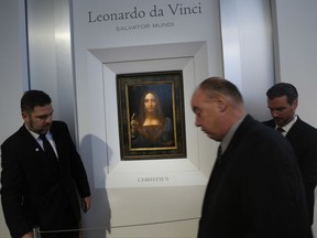 Security guards set up a rope in front of "Salvator Mundi" by Leonardo da Vinci during a news conference at Christie's in New York, Tuesday, Oct. 10, 2017. The piece, which was painted around 1500, is one of fewer than twenty da Vinci paintings known to exist. After public exhibitions around the world, the auction is scheduled to take place on Nov. 15, 2017. (AP Photo/Seth Wenig)