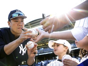 New York Yankees starting pitcher Masahiro Tanaka, left, gives autographs to youngsters before the Yankees' final regular season baseball game, against the Toronto Blue Jays in New York, Sunday, Oct. 1, 2017. (AP Photo/Kathy Willens)