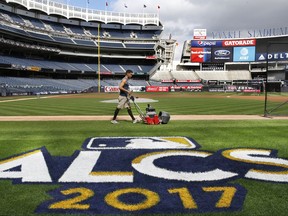 A groundskeeper mows the grass around a recently painted field logo before an American League Championship Series baseball workout day at Yankee Stadium in New York, Sunday, Oct. 15, 2017. (AP Photo/Kathy Willens)