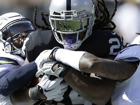 Oakland Raiders running back Marshawn Lynch, center, is tackled by Los Angeles Chargers strong safety Adrian Phillips, left, and free safety Tre Boston during the first half of an NFL football game in Oakland, Calif., Sunday, Oct. 15, 2017. (AP Photo/Ben Margot)