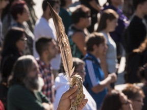 An Indigenous leader holds up an eagle's feather during a vigil.