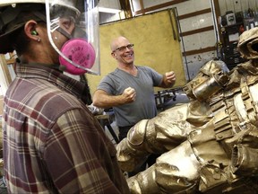 Alan Cottrill, right, a well-known Zanesville, Ohio sculptor, has been commissioned by the National Infantry Museum in Georgia to create nine 7-foot sculptures of combat soldiers for the Global War on Terror Memorial. Working on one of the sculptures in Cottrill's studio is Dan Minosky, left. [Fred Squillante/The Columbus Dispatch via AP)