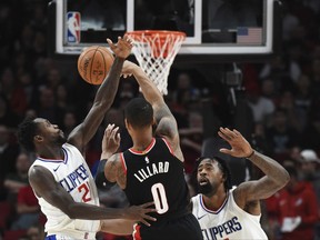 Portland Trail Blazers guard Damian Lillard (0) passes the ball over Los Angeles Clippers guard Patrick Beverley during the first quarter of an NBA basketball game in Portland, Ore., Thursday, Oct. 26, 2017. (AP Photo/Steve Dykes)