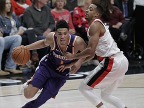 Phoenix Suns guard Devin Booker, left, drives to the basket as Portland Trail Blazers guard CJ McCollum defends during the first half of an NBA basketball game in Portland, Ore., Saturday, Oct. 28, 2017. (AP Photo/Steve Dipaola)