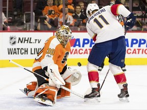 Philadelphia Flyers' Michal Neuvirth, left, stops the puck as it pops up between him and Florida Panthers' Jonathan Huberdeau during the first period of an NHL hockey game, Tuesday, Oct. 17, 2017, in Philadelphia. (AP Photo/Chris Szagola)
