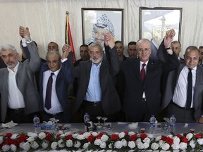 In this Oct. 2, 2017 file photo from left in front row, Hamas leader in the Gaza Strip Yahya Sinwar, Head of Palestinian General Intelligence Majid Faraj, Head of the Hamas political bureau Ismail Haniyeh, Palestinian Prime Minister Rami Hamdallah and an Egyptian mediator hold their hands up during a meeting in Gaza City