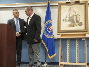 FILE – In this March 31, 2017, file photo, John Grant, right, shakes hands with FBI Special Agent Jacob Archer, left, after taking custody of a recovered Norman Rockwell painting stolen during a 1976 break-in at the Grant family's home in Cherry Hill, N.J., at a news conference at the federal building in Philadelphia. The 1919 painting recently returned to a family after it was stolen from their New Jersey home more than 40 years ago is going up for auction. (AP Photo/Matt Rourke, File)