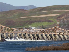 FILE - This May 12, 2011, file photo shows The Dalles Dam behind The Dalles Bridge on the Columbia River, in The Dalles, Ore. Members of Congressional delegations from Oregon and Washington state say the Trump administration has walked away from the federal government's obligation to build new homes and villages for Indians whose original abodes were submerged by the building of dams along the Columbia River decades ago. (AP Photo/Rick Bowmer, file)