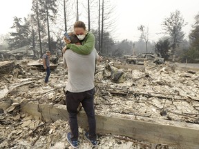 FILE--In this Oct. 10, 2017, file photo,Todd Caughey hugs his daughter Ella as they visit the site of their home destroyed by fires in Kenwood, Calif. For many residents in the path of one of California's deadliest blazes, talk is of wind direction, evacuations and goodbyes. (AP Photo/Jeff Chiu, file)