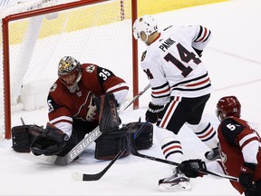 Chicago Blackhawks' Richard Panik (14) scores a goal against Arizona Coyotes' Louis Domingue (35) as Coyotes' Jason Demers (55) looks on during the first period of an NHL hockey game Saturday, Oct. 21, 2017, in Glendale, Ariz. (AP Photo/Ross D. Franklin)