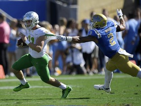 Oregon quarterback Braxton Burmeister, left, breaks a tackle by UCLA linebacker Josh Woods during the first half of an NCAA college football game, Saturday, Oct. 21, 2017, in Pasadena, Calif. (AP Photo/Mark J. Terrill)