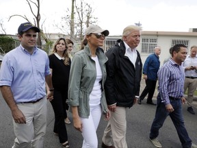 President Donald Trump and first lady Melania Trump take a walking tour with Puerto Rico Governor Ricardo Rosselló, left, and his wife Beatriz Areizaga to survey hurricane damage and recovery efforts in a neighborhood in Guaynabo, Puerto Rico, Tuesday, Oct. 3, 2017. (AP Photo/Evan Vucci)