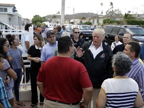 President Donald Trump and Puerto Rico Governor Ricardo Rosselló, center, listen to residents and survey hurricane damage and recovery efforts in a neighborhood in Guaynabo, Puerto Rico, Tuesday, Oct. 3, 2017. (AP Photo/Evan Vucci)