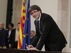 Catalan regional President Carles Puigdemont signs an independence declaration document after a parliamentary session in Barcelona, Spain, Tuesday, Oct. 10, 2017. Puigdemont says he has a mandate to declare independence for the northeastern region, but proposes waiting "a few weeks" in order to facilitate a dialogue. (AP Photo/Manu Fernandez)
