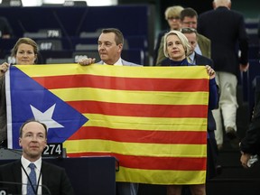 Belgium members of the European Parliament, Anneleen Van Bossuyt, left, Mark Demesmaeker and Helga Stevens, right, display a Catalan flag in support of the disputed independence vote Sunday in Catalonia during a session at the European Parliament in Strasbourg, eastern France, Wednesday, Oct. 4, 2017. European Commission Vice President Frans Timmermans says there is a "general consensus that regional government of Catalonia has chosen to ignore the law when organizing the referendum." (AP Photo/Jean-Francois Badias)