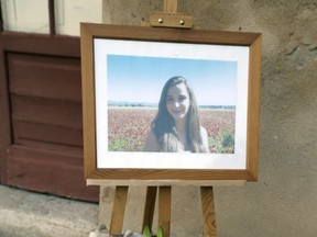 A portrait of Mauranne, 20, who was fatally stabbed along with her cousin, Laura, 21, at the Marseille Saint Charles train station, is displayed while residents of Eguilles, near Marseille, southern France, sign the book of condolence in front of the city hall, Monday, Oct. 2, 2017. The assailant was killed by soldiers immediately after the attacks, the latest of several targeting France. (AP Photo/Claude Paris)