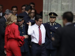 Mexican President Enrique Pena Nieto puts on his jacket as his wife Angelica Rivera looks on before welcoming Canadian Prime Minister Justin Trudeau and his wife Sophie Gregoire Trudeau to the National Palace in Mexico City, Thursday, Oct. 12, 2017.  (AP Photo/Rebecca Blackwell)
