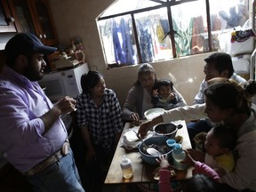 In this Aug. 23, 2017 photo, Juana Pedraza, center, holds her one-year-old grandson Jose Leonardo, who they call Leon, as the family eats breakfast in their home in Villa Cuauhtemoc, Mexico state. The gruesome death of Pedraza's 29-year-old daughter Jessica, Leo's mother, was part of a wave of killings of women plaguing the sprawling State of Mexico. From left are Jessica's former partner and Leo's father, Alejandro Garcia, Jessica's sister Zurisadai, father Abel, and sister Diana Laura with her two children. (AP Photo/Rebecca Blackwell)