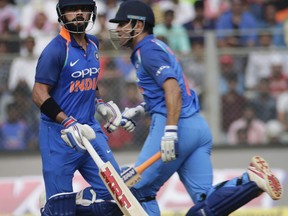 India's captain Virat Kohli, left, and Mahendra Singh Dhoni run between the wickets during their first one-day international cricket match against New Zealand in Mumbai, India, Sunday, Oct. 22, 2017. (AP Photo/Rafiq Maqbool)