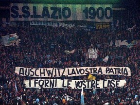 FILE - In this Nov. 29, 1998 file photo, Lazio fans display banners from the stands reading "Auschwitz is Your Homeland. The Ovens are Your Homes" during a Serie A match between Lazio and AS Roma, at Rome's Olympic stadium. Lazio fans have a long history of racism and anti-Semitism but the Roman club's supporters established a new low on Sunday, Oct. 22,  2017 when they littered the Stadio Olimpico with superimposed images of Anne Frank _ the young diarist who died in the Holocaust _ wearing a Roma jersey.  (AP Photo/Plinio Lepri, files)