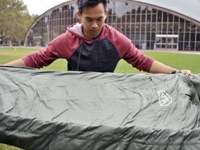 In this Oct. 6, 2017 photo, Vick Liu displays his TravlerPack, a lightweight sleeping bag, outside the Kresge Auditorium at the Massachusetts Institute of Technology in Cambridge, Mass . Liu, a finance and political science major, created a line of lightweight sleeping bags for refugees who have few other options to keep warm during winters in the Middle East. Liu and a team of five classmates are sending sleeping bags to resettlement areas in Syria and hope to send more to refugees in Jordan and Lebanon. (AP Photo/Collin Binkley)