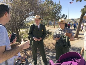 Acting National Park Service director Mike Reynolds, center, speaks to a visitor at Grand Canyon National Park, Ariz., Friday, Oct. 13, 2017. Reynolds earlier released the results of a Park Service survey that found nearly two in five workers permanent employees have experienced harassment or discrimination. (AP Photo/Felicia Fonseca)
