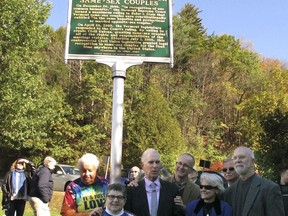 People stand below an historic site marker commemorating Vermont's first-in-the-nation civil union law and subsequent marriage equality legislation after it was unveiled on the State House lawn, Tuesday, Oct. 17, 2017, in Montpelier, Vt. Posing below the marker are from left: Lois Farnham, Holly Puterbaugh, Stan Baker and Peter Harrigan, plaintiffs in a Supreme Court case that led to civil unions, as well as Beth Robinson, a lawyer who served as co-counsel in the case and now a Vermont Supreme Court justice, and state Rep. Bill Lippert, D-Hinesburg. (AP Photo/Lisa Rathke)