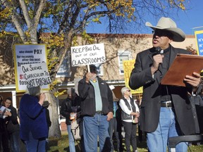 Roman Catholic Pastor Vincent Paul Chavez, right, of the Saint Therese school and parish in Albuquerque, protests proposed state science standards on behalf of the Santa Fe Archdiocese outside a public hearing in Santa Fe, N.M., Monday, Oct. 16, 2017. The proposed standards for public schools has come under intense criticism for omitting or deleting references to global warming, evolution and the age of the Earth. Comments at the hearing overwhelmingly sided against state revisions to a set of standards developed by a consortium of states and the National Academy of Sciences. (AP Photo/Morgan Lee)