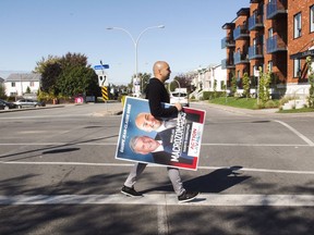 Former Canadian Olympic sprinter Nick Macrozonaris puts up campaign posters in Ste-Dorothee, Que., Friday, October 13, 2017. Macrozonaris is running for city council in the upcoming municipal elections. THE CANADIAN PRESS/Ryan Remiorz