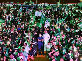 FILE - In this Sept. 23, 2017 file photo released by Saudi Press Agency, SPA, Saudi men and women attend national day ceremonies at the King Fahd stadium in Riyadh, Saudi Arabia. Women will be allowed into sports stadiums as of next year, the kingdom's latest step toward easing rules on gender segregation -- but they will only be allowed to sit in the so-called family section. (Saudi Press Agency via AP, File)