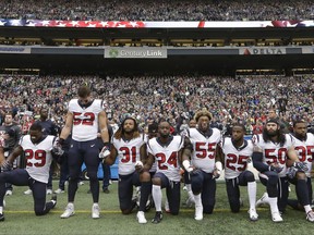 Houston Texans players kneel and stand during the singing of the national anthem before an NFL football game against the Seattle Seahawks, Sunday, Oct. 29, 2017, in Seattle. (AP Photo/Elaine Thompson)