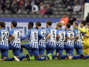 Players of Berlin kneel down prior to the German Bundesliga soccer match between Hertha BSC Berlin and FC Schalke 04 in Berlin, Germany, Saturday, Oct. 14, 2017. Hertha Berlin nodded to social struggles in the United States by kneeling before its Bundesliga game at home to Schalke on Saturday. Hertha's starting lineup linked arms and took a knee on the pitch, while coaching staff, officials and substitutes took a knee off it. The action was intended to show solidarity with NFL players who have been demonstrating against discrimination in the US by kneeling, sitting or locking arms through the anthem before games.  (AP Photo/Michael Sohn)