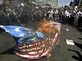 FILE- In this Friday, Aug. 13, 2004 file photo, Protesters burn a U.S. flag during a demonstration against U.S-led coalition actions in Iraq at the Enqelab (Revolution) Sq. in Tehran, Iran. (AP Photo/Vahid Salemi, File)