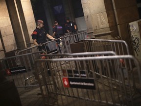 Spanish police officers set up barriers outside the Parliament of Catalonia in Barcelona, Spain, Tuesday Oct. 10, 2017. Catalan regional President Carles Puigdemont plans to address the Catalan parliament on Tuesday evening in a session that some have portrayed as the staging of an independence declaration for the northeastern region of 7.5 million, although others have said the move would only be symbolic. (AP Photo/Emilio Morenatti)