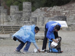 Officials try to dry rain from the cauldron before the lighting ceremony of the Olympic flame in Ancient Olympia, southwestern Greece, on Tuesday, Oct. 24, 2017. The flame will be transported by torch relay to Pyeongchang, South Korea, which will host the Feb. 9-25, 2018 Winter Olympics. (AP Photo/Thanassis Stavrakis)