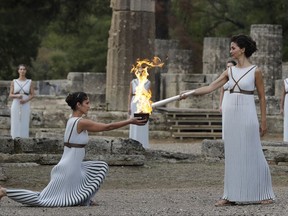 Actress Katerina Lehou, right, as high priestess, lights the torch during the lighting ceremony of the Olympic flame in Ancient Olympia, southwestern Greece, on Tuesday, Oct. 24, 2017. The flame will be transported by torch relay to Pyeongchang, South Korea, which will host the Feb. 9-25, 2018 Winter Olympics. (AP Photo/Thanassis Stavrakis)