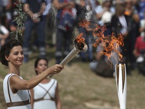 Actress Katerina Lehou as high priestess, passes the Olympic Flame onto a Pyeongchang torch bearer after it was lit from the sun's rays, during the final dress rehearsal for the lighting of the Olympic flame at Ancient Olympia, southwestern Greece on Monday, Oct. 23, 2017. The flame will be transported by torch relay to Pyeongchang, South Korea, which will host the Feb. 9-25, 2018 Winter Olympics. (AP Photo/Petros Giannakouris)