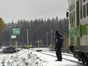 Rescue, military personnel and a policeman gather at the railroad crossing, where several people were killed in a crash between a train, right, and a military truck, left, by the track, in southern Finland Thursday Oct. 26, 2017.  Finnish media say several people have been killed in a train crash in the southern part of Finland. (Lehtikuva via AP)