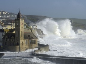 Waves break around the church in the harbour at Porthleven, Cornwall southwestern England, as the remnants of  Hurricane Ophelia begins to hit parts of Britain and Ireland. Ireland's meteorological service is predicting wind gusts of 120 kph to 150 kph (75 mph to 93 mph), sparking fears of travel chaos. Some flights have been cancelled, and aviation officials are warning travelers to check the latest information before going to the airport Monday.  (Ben Birchall/PA via AP)