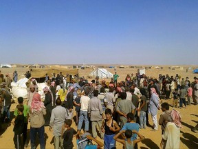FILE - In this Aug. 4, 2016 file photo, people gather to take basic food stuffs and other aid from community leaders charged with distributing equitably the supplies to the 64,000-person refugee camp called Ruqban on the Jordan-Syria border. The U.N. humanitarian chief has called for immediate access to deliver "life-saving assistance" to 50,000 Syrians stranded on the sealed border with Jordan, amid reports of shrinking food supplies. (AP Photo/File)