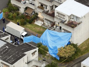 Plastic blue sheets cover an apartment where dead bodies were found after a fire in Hitachi, Ibaraki prefecture eastern Japan Friday, Oct. 6, 2017. The apartment fire has killed six people, and a man turned himself in and was arrested on suspicion of murder. Police say six bodies were found in the building, believed to be the wife and five children of the man. (Maya Matsumoto/Kyodo News via AP)