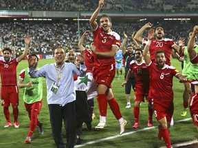 FILE - In this Sept. 5, 2017 file photo, Syria's national soccer team celebrates at the conclusion of their match with Iran which drew 2-2 during their Round 3 - Group A World Cup qualifier at the Azadi Stadium in Tehran, Iran.  Regardless of how Syria does in its World Cup playoff against Australia, the team has helped football knock fighting out the headlines for a while in their war-torn country. The Syrians are still in contention to qualify for the World Cup for the first time, and the journey to their biggest match so far has captured domestic and international attention.(AP Photo/Vahid Salemi, File)